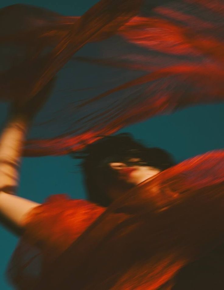 Figura em movimento envolvida por tecido vermelho