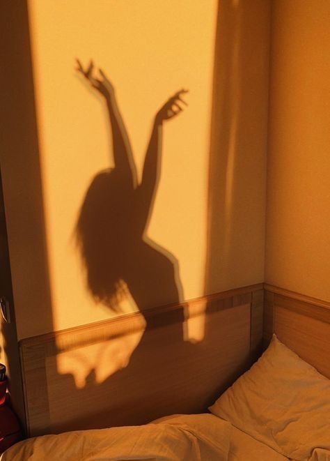 Sombra feminina projetada por luz dourada